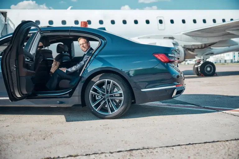 cheerful-man-elegant-suit-is-getting-out-automobile-after-transfer-jet-before-departure-scaled